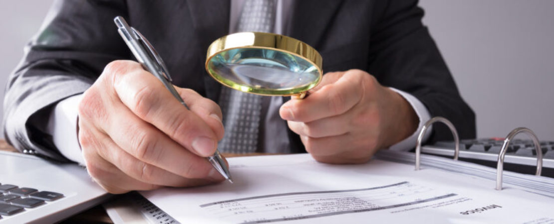 Businessperson Looking At Receipts Through Magnifying Glass